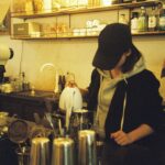 a woman standing at a counter in a coffee shop