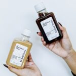 Hands holding two bottles of coffee.