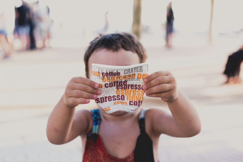 child wearing black and red spaghetti strap top standing while holding disposable coffee cup
