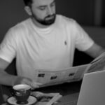 a man sitting at a table reading a newspaper